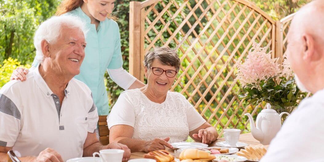 Elderly Couple Dining Outdoors with Nurse at Independent Living Facility