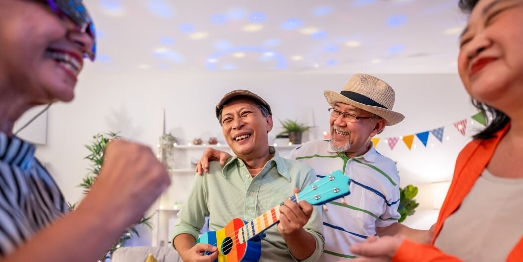Elderly Group Singing and Laughing Together While Holding Instruments Indoors at a Senior Living Community