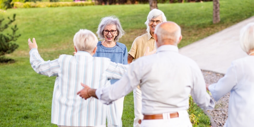 Group of Seniors Greeting Each Other Outdoors at an Independent Living Facility