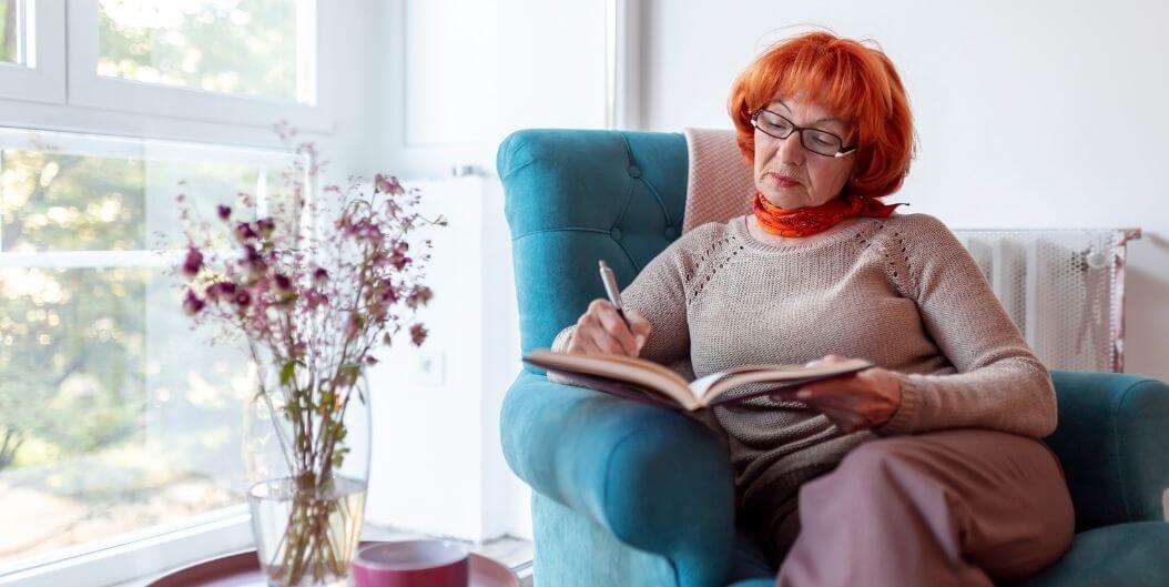 Elderly Woman Writing Memoir on Armchair at Independent Living Facility