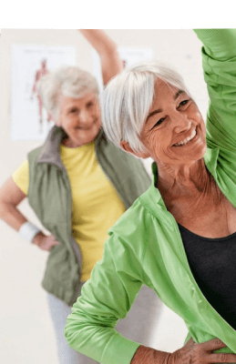 Two Elderly Women Stretching During an Exercise Class at an Independent Living Community Two Elderly Women Stretching During an Exercise Class at an Independent Living Community