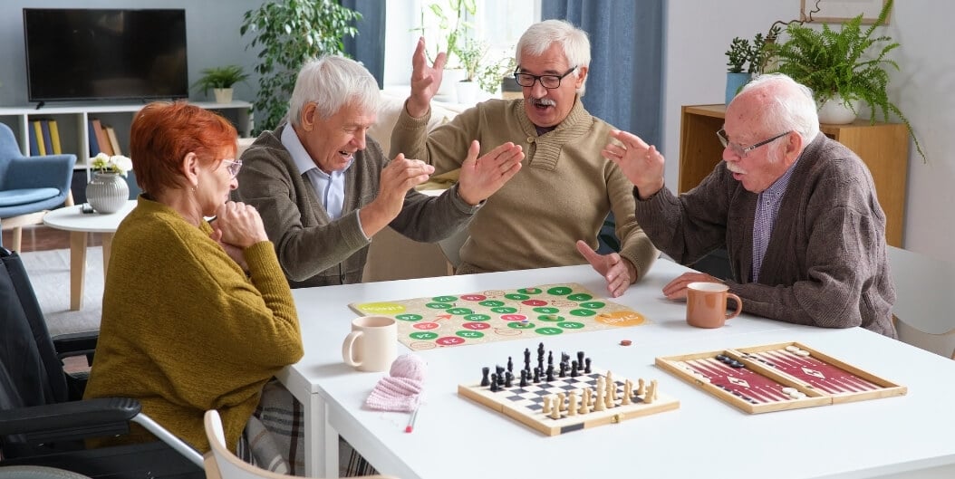 Elderly Friends Playing Board Games in Game Room at Independent Living Facility